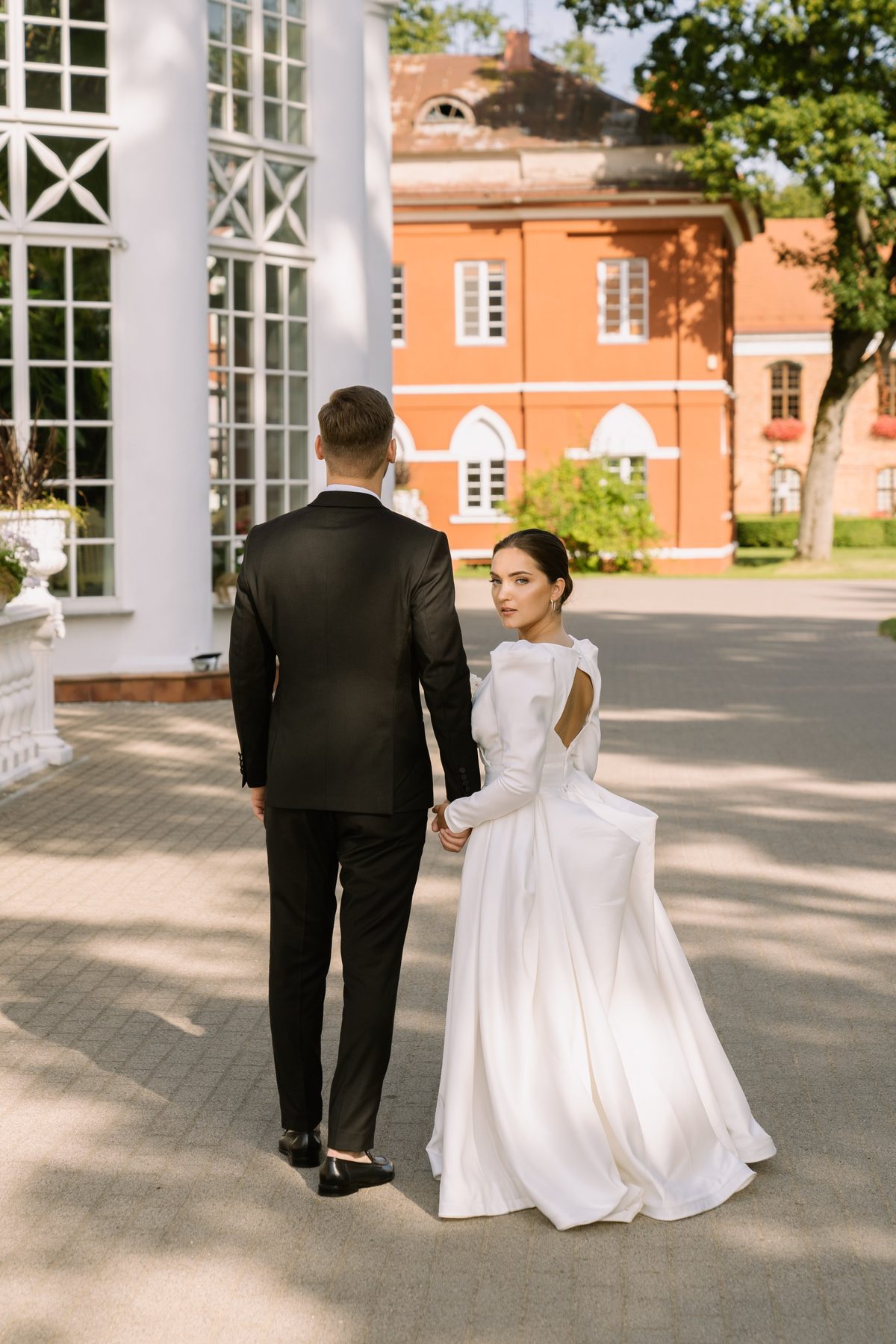 Jaunoji atsigręžia eidama su jaunuoju dvaro kieme